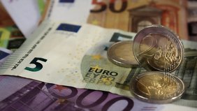 Eurobanknoten und Münzen, darunter ein 5-Euro-Schein und eine 100-Euro-Note.